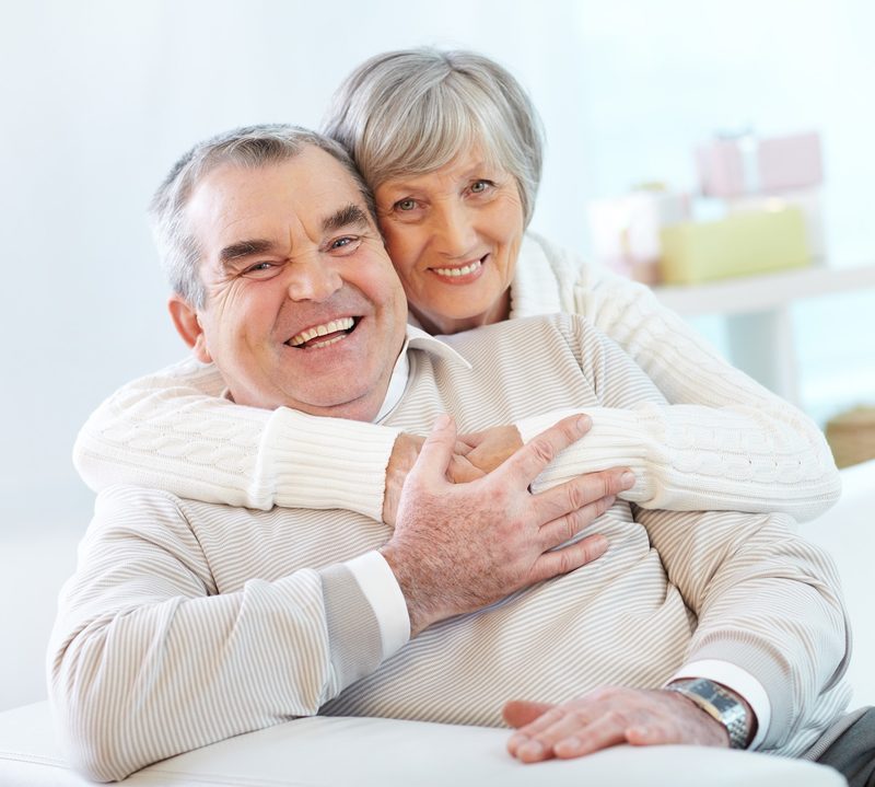 Casal de idosos sorrindo abraçados